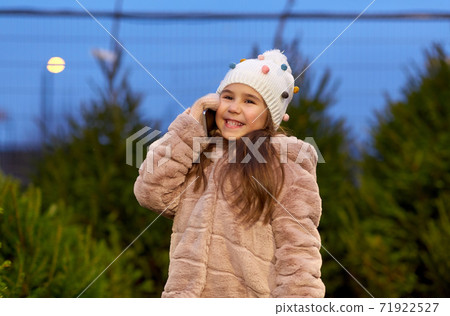 girl calling on smartphone over christmas trees girl calling on smartphone over christmas trees 71922527