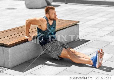 young man doing triceps dip on city street 71922657