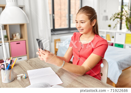 girl with smartphone distracting from homework 71922686