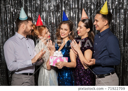 happy friends in party hats with birthday gift happy friends in party hats with birthday gift 71922709