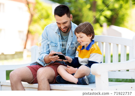 father and son with smartphone at park 71922737