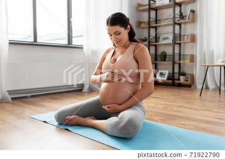 happy pregnant woman sitting on yoga mat at home happy pregnant woman sitting on yoga mat at home 71922790
