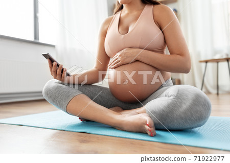 happy pregnant woman with phone doing yoga at home happy pregnant woman with phone doing yoga at home 71922977