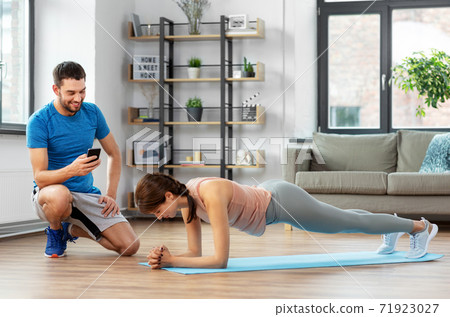 woman with personal trainer doing plank at home 71923027