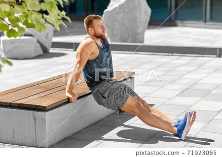 young man doing triceps dip on city street young man doing triceps dip on city street 71923065