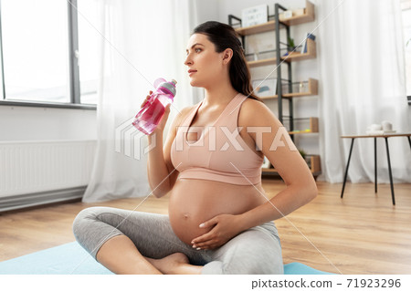 pregnant woman drinking water after yoga at home 71923296