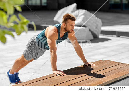 young man doing push ups on city street young man doing push ups on city street 71923311