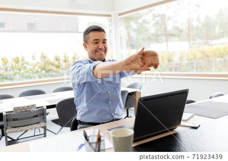 tired man with laptop stretching at home office 71923439