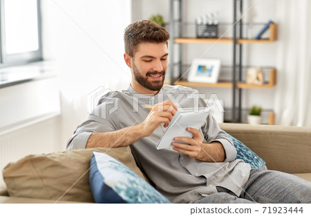 smiling man writing to notebook at home smiling man writing to notebook at home 71923444