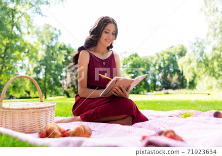 happy woman with diary and picnic basket at park 71923634