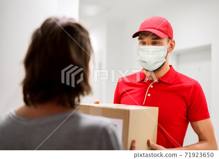 delivery man in mask giving parcel box to customer delivery man in mask giving parcel box to customer 71923650