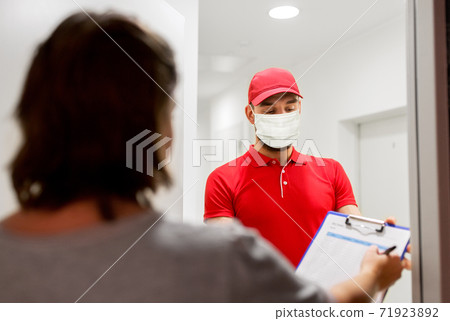 delivery man in mask and customer signing papers delivery man in mask and customer signing papers 71923892