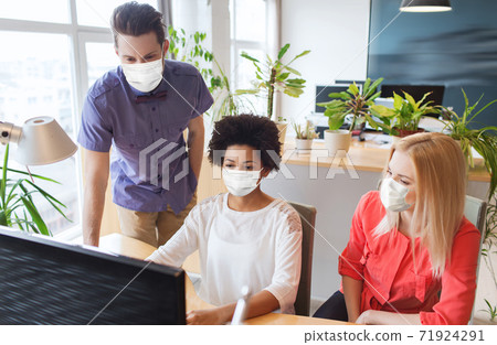 creative team in masks with computer at office creative team in masks with computer at office 71924291