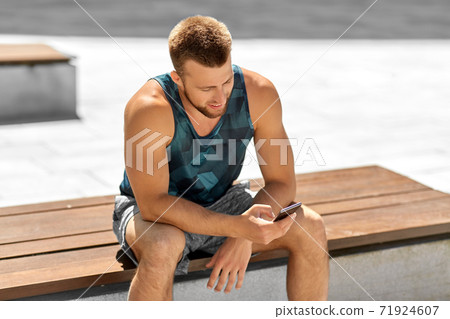 man with smartphone sitting on bench outdoors man with smartphone sitting on bench outdoors 71924607