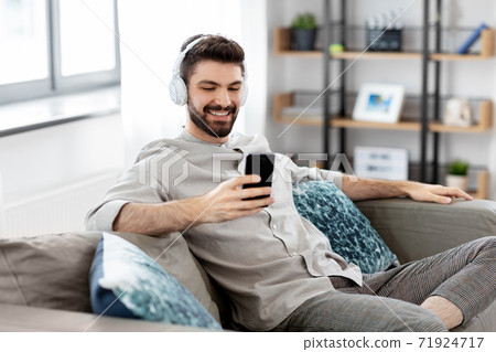 man in headphones listening to music on smartphone 71924717