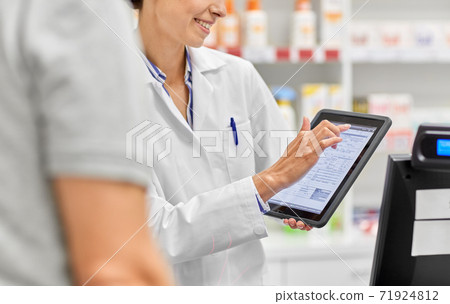 female pharmacist with prescription on tablet pc 71924812