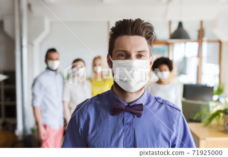 young man in mask over creative team at office young man in mask over creative team at office 71925000