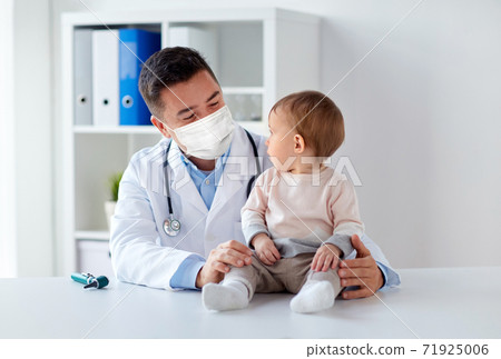 doctor or pediatrician in mask with baby at clinic doctor or pediatrician in mask with baby at clinic 71925006