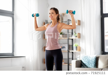 smiling young with dumbbells exercising at home 71925111
