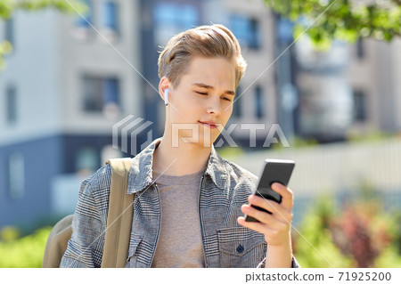 teenage boy with earphones and smartphone in city teenage boy with earphones and smartphone in city 71925200