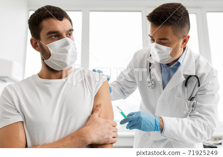 patient and doctor in masks doing vaccination patient and doctor in masks doing vaccination 71925249