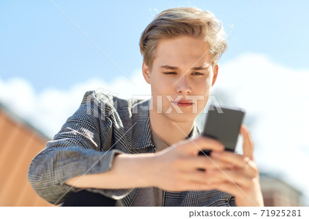 young man or teenage boy using smartphone outdoors 71925281
