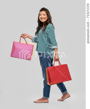 happy asian woman walking with shopping bags happy asian woman walking with shopping bags 71925339