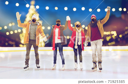 friends in masks waving hands on skating rink 71925385