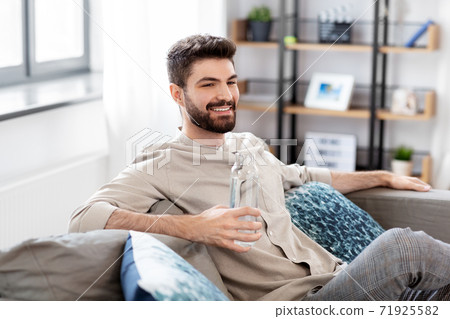 happy man drinking water from glass bottle at home happy man drinking water from glass bottle at home 71925582