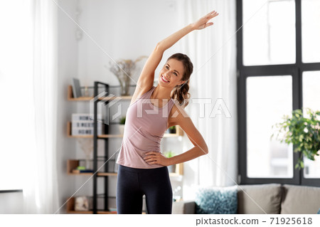 smiling young woman exercising at home smiling young woman exercising at home 71925618