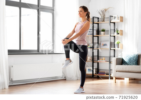 smiling young woman stretching leg at home smiling young woman stretching leg at home 71925620