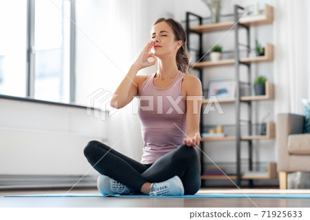 woman doing yoga in lotus pose at home 71925633