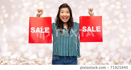 happy asian woman with shopping bags over lights happy asian woman with shopping bags over lights 71925840