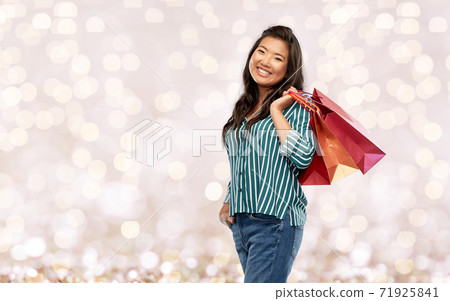 happy asian woman with shopping bags over lights happy asian woman with shopping bags over lights 71925841