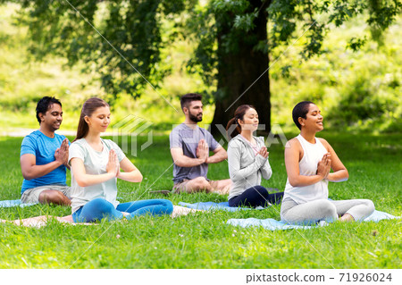 group of happy people doing yoga at summer park 71926024