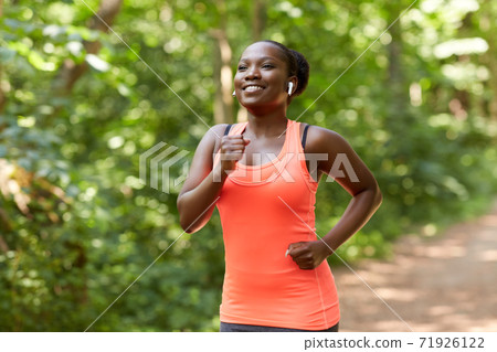 happy african woman in earphones running in park happy african woman in earphones running in park 71926122