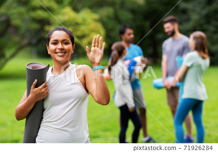 smiling woman with yoga mat waving hand at park smiling woman with yoga mat waving hand at park 71926284