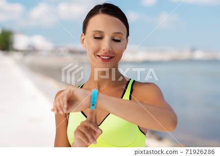smiling young woman with fitness tracker outdoors smiling young woman with fitness tracker outdoors 71926286