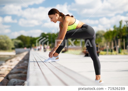 sporty woman tightening shoelaces outdoors sporty woman tightening shoelaces outdoors 71926289