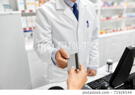 close up of hand giving bank card to pharmacist close up of hand giving bank card to pharmacist 71926544