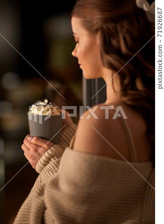 woman holding mug with whipped cream at night 71926687