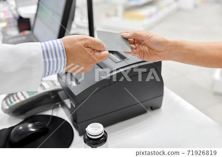 close up of hand giving bank card to pharmacist close up of hand giving bank card to pharmacist 71926819