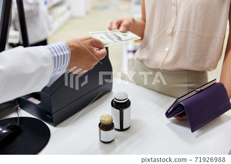 pharmacist taking money from customer at pharmacy pharmacist taking money from customer at pharmacy 71926988