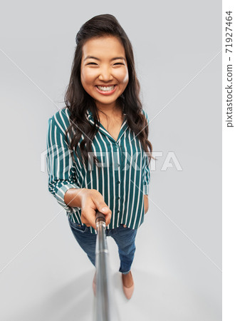 happy asian woman taking picture with selfie stick happy asian woman taking picture with selfie stick 71927464