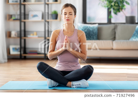 woman doing yoga in lotus pose at home woman doing yoga in lotus pose at home 71927496