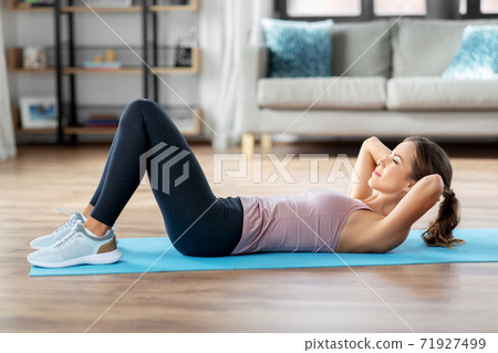 young woman exercising and doing sit-ups at home young woman exercising and doing sit-ups at home 71927499