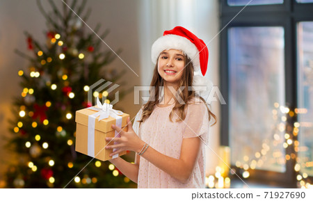 teenage girl in santa hat with christmas gift 71927690