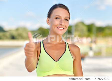 portrait of smiling sporty woman showing thumbs up portrait of smiling sporty woman showing thumbs up 71927899