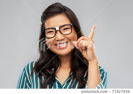 happy asian woman in glasses pointing finger up happy asian woman in glasses pointing finger up 71927936