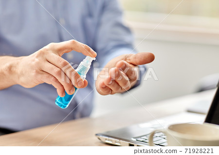 man using hand sanitizer at home office man using hand sanitizer at home office 71928221
